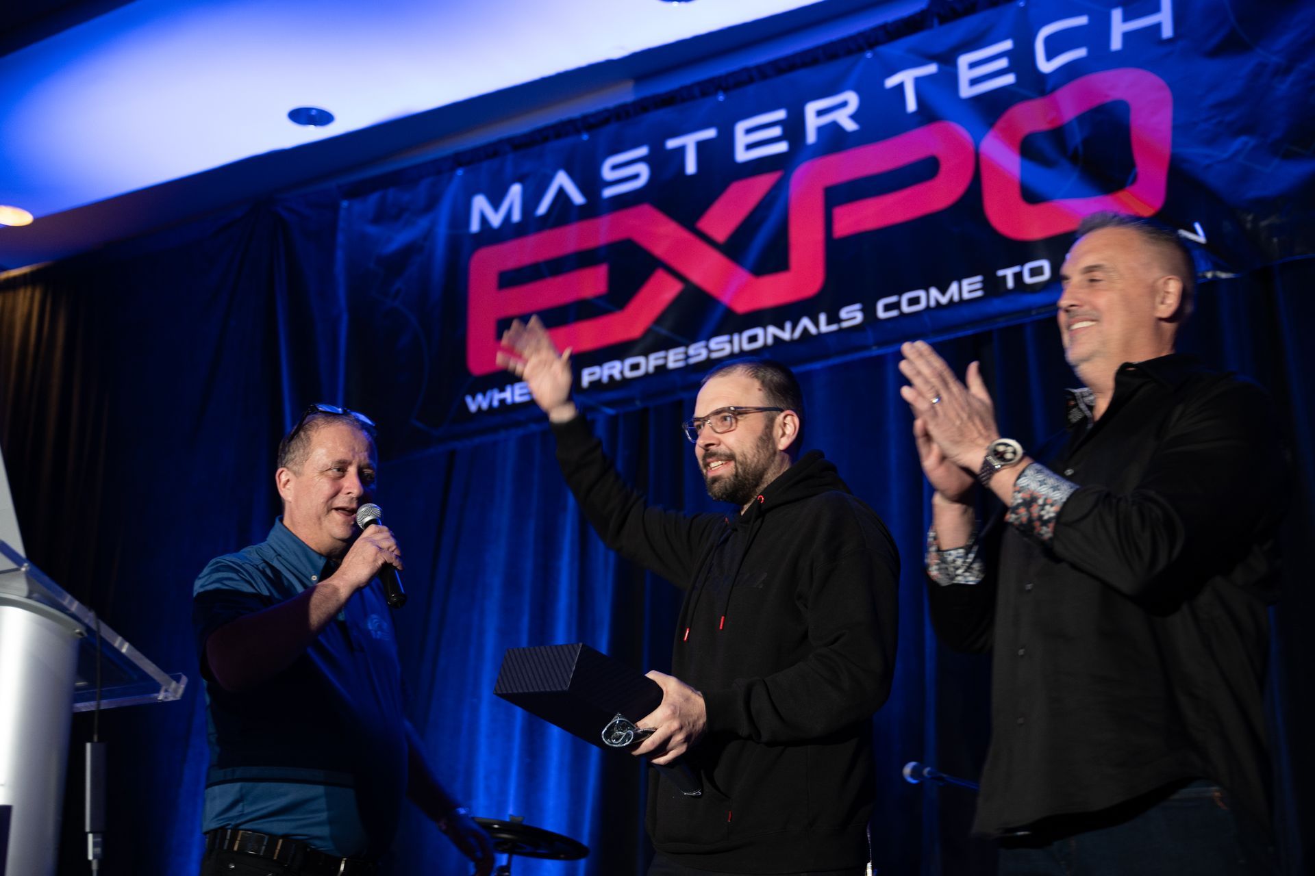 Three men on stage at 