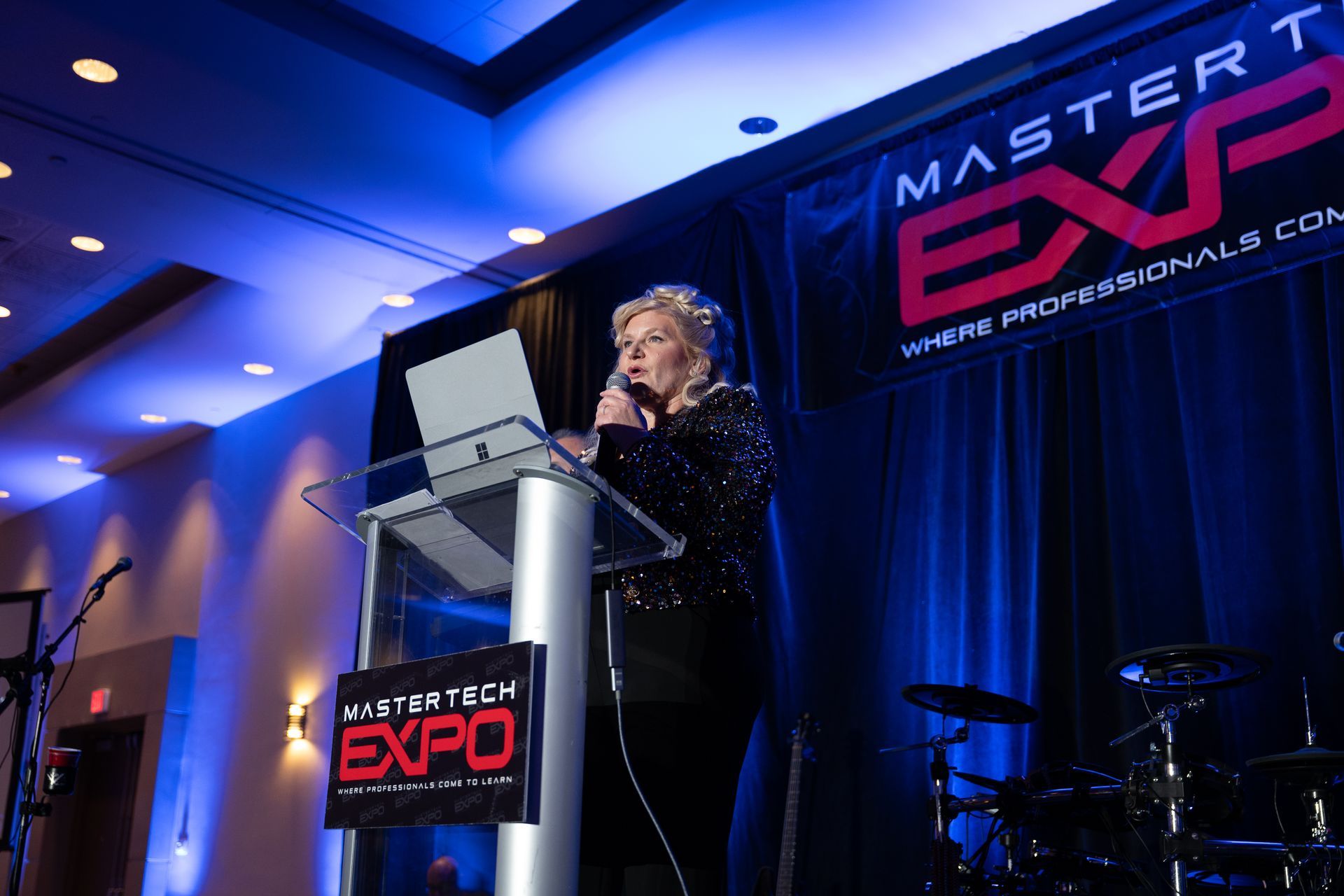 Woman speaking at a podium with a laptop, at a 