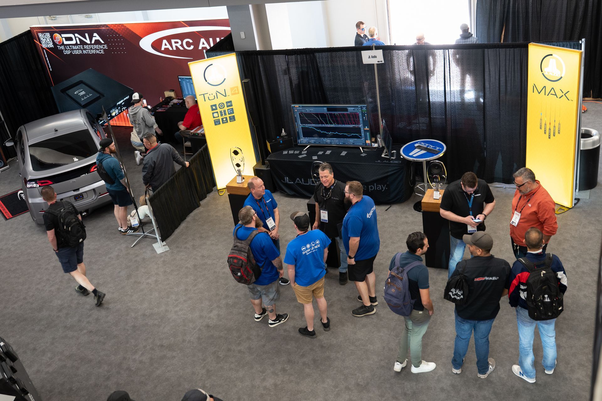 Trade show booth with people in blue shirts, testing equipment, and banners.