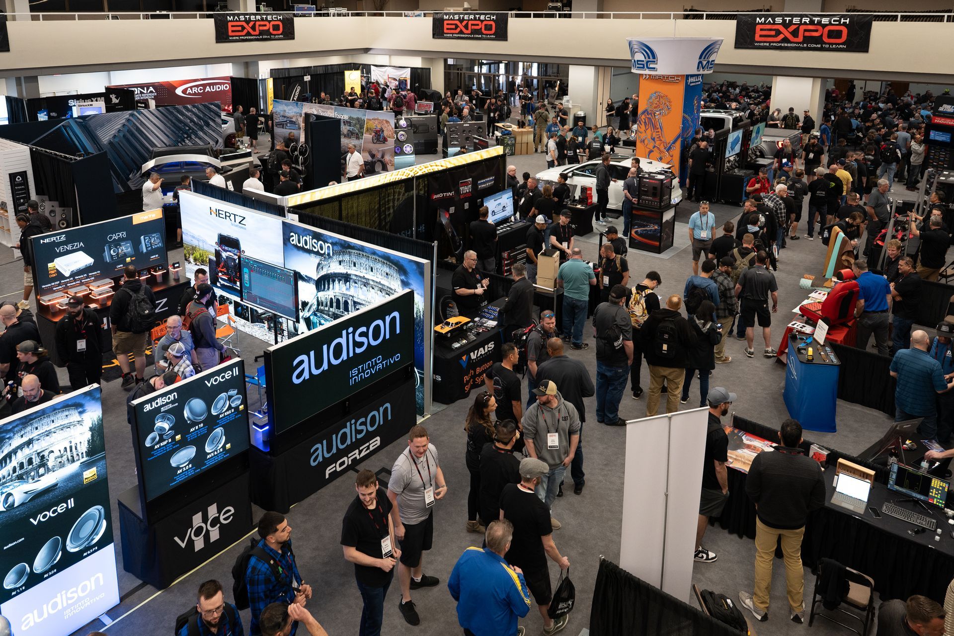 Large exhibition hall filled with people. Booths, displays, and products are visible.