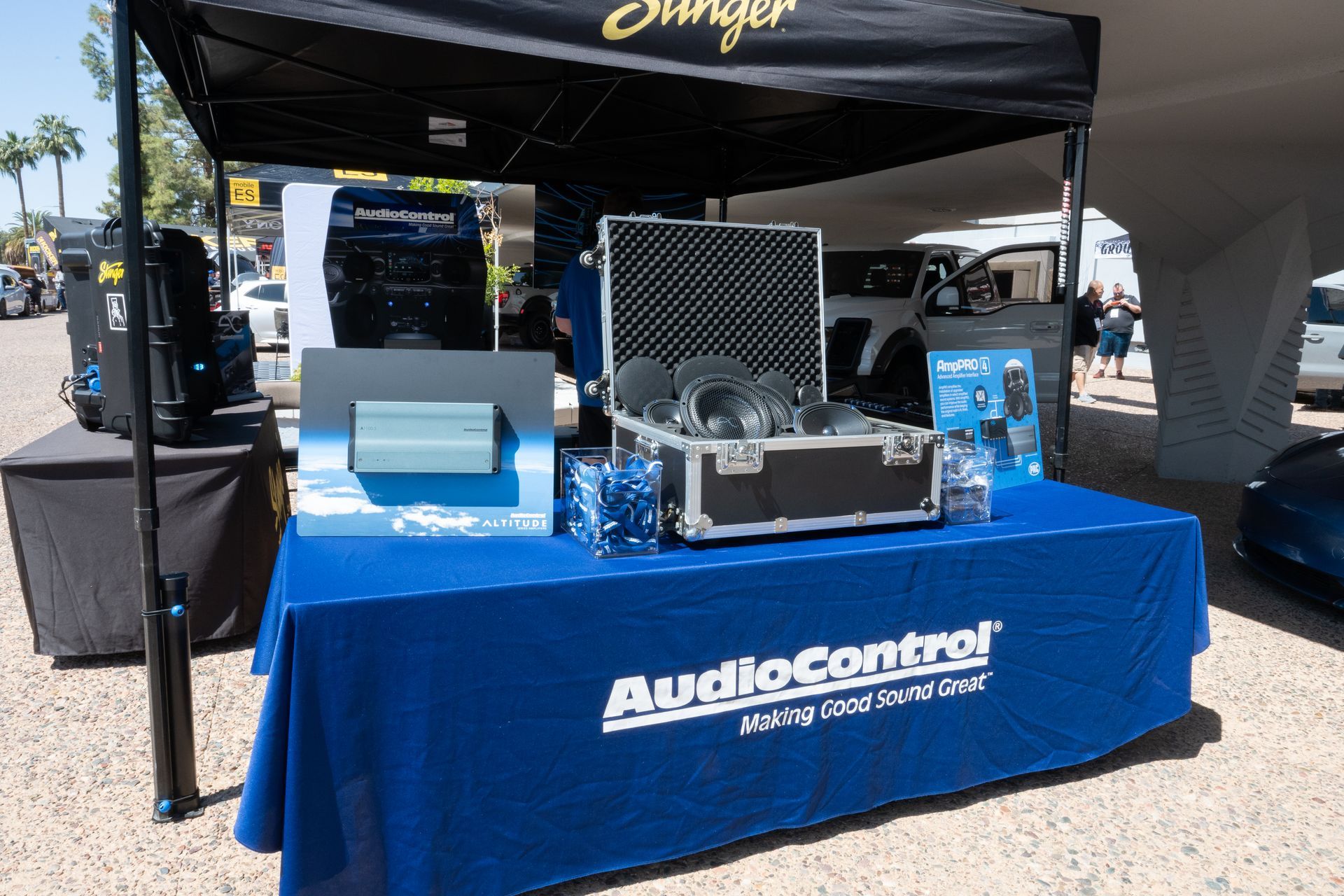 AudioControl booth with equipment on a table covered in a blue tablecloth at an outdoor event.