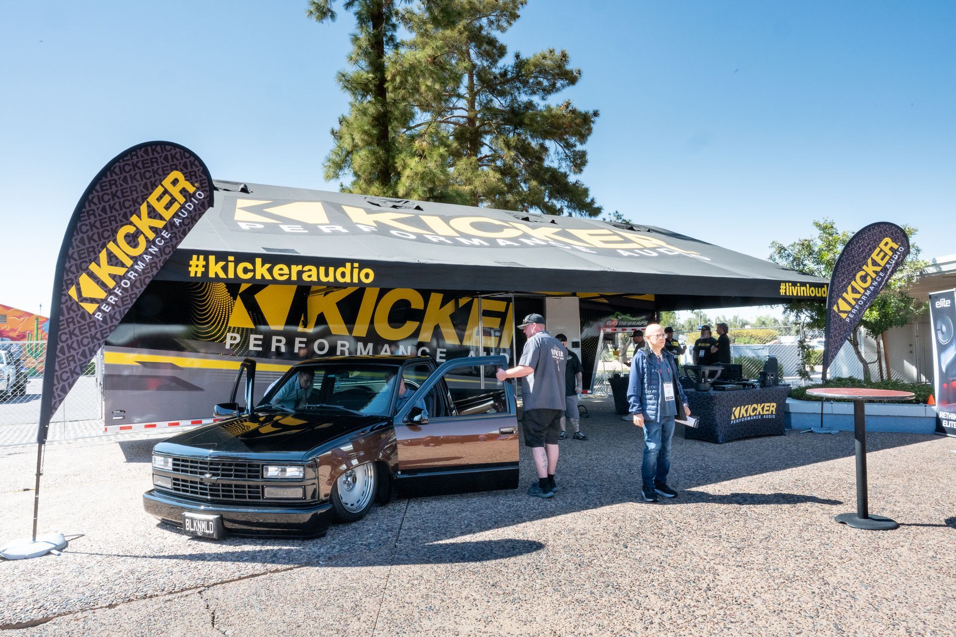 Kicker audio booth at an outdoor event, with a custom truck and people looking at displays.