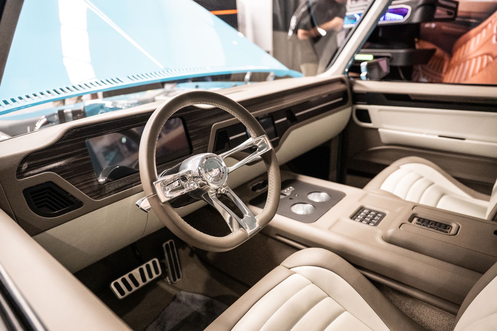Classic car interior with beige and white upholstery, chrome steering wheel, and digital dashboard.