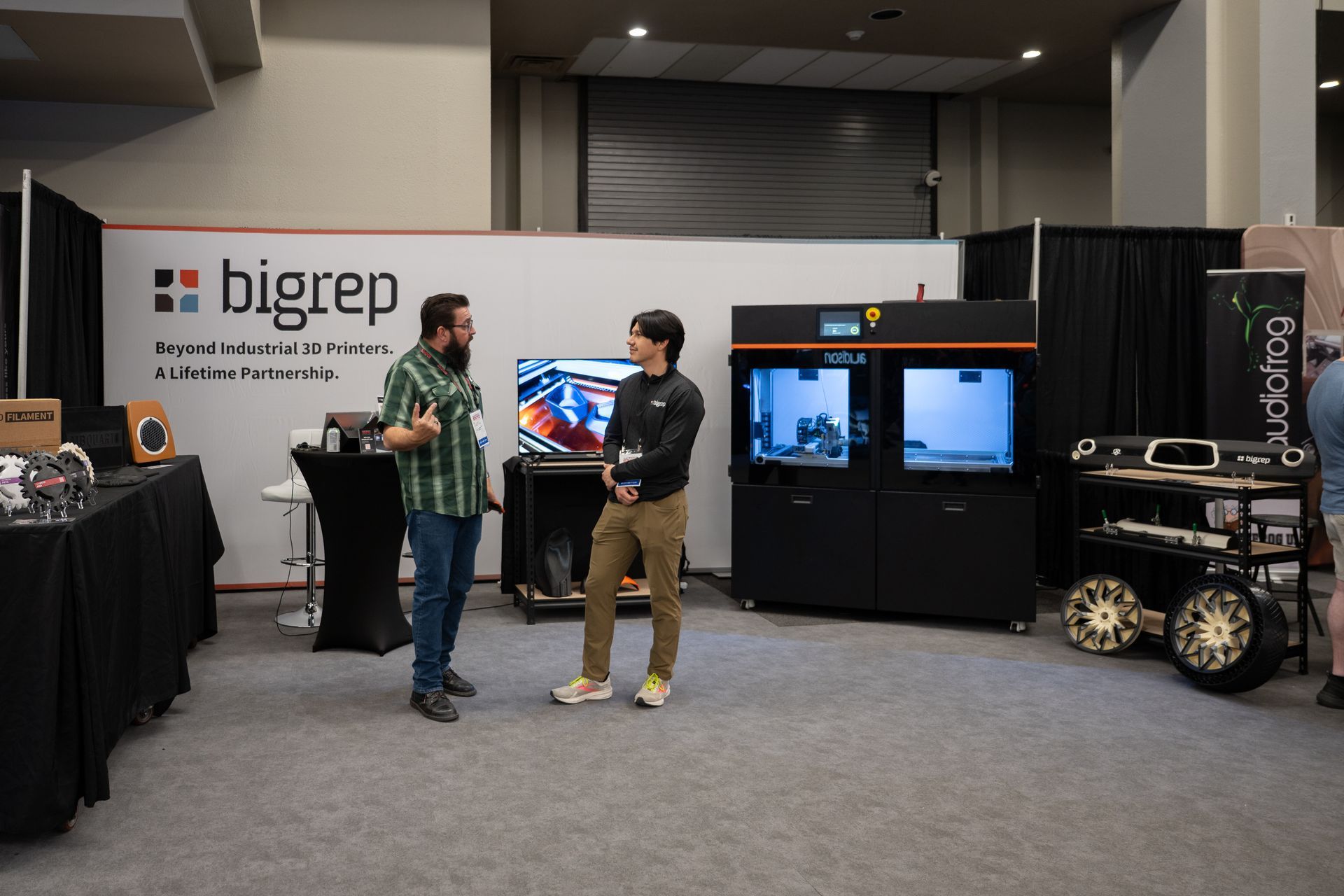 Two men conversing at a trade show booth, 