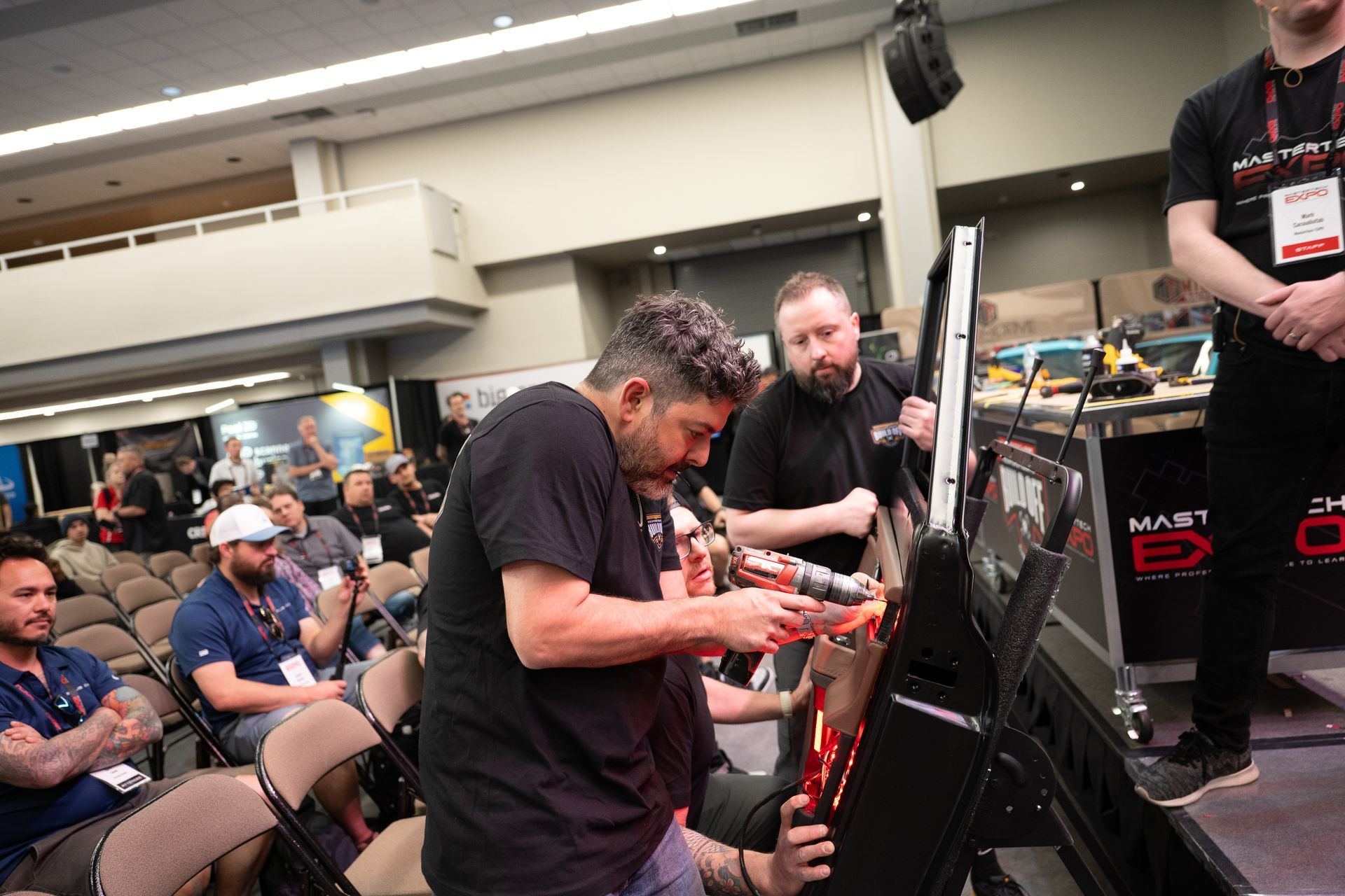 Man assembles equipment at event, others watch.