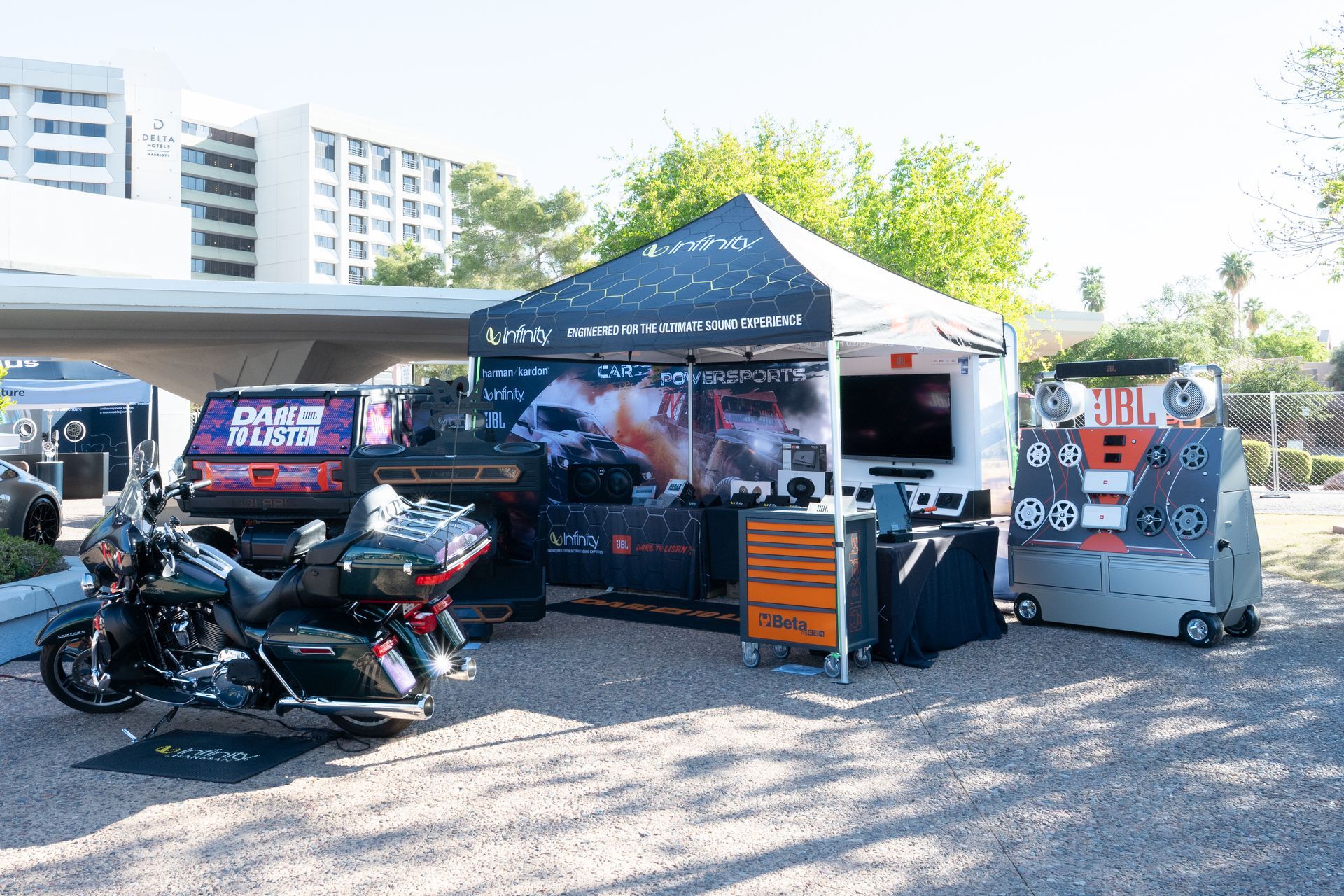 Motorcycle and display tent at an outdoor event. Tent has a TV, tools, and graphics.