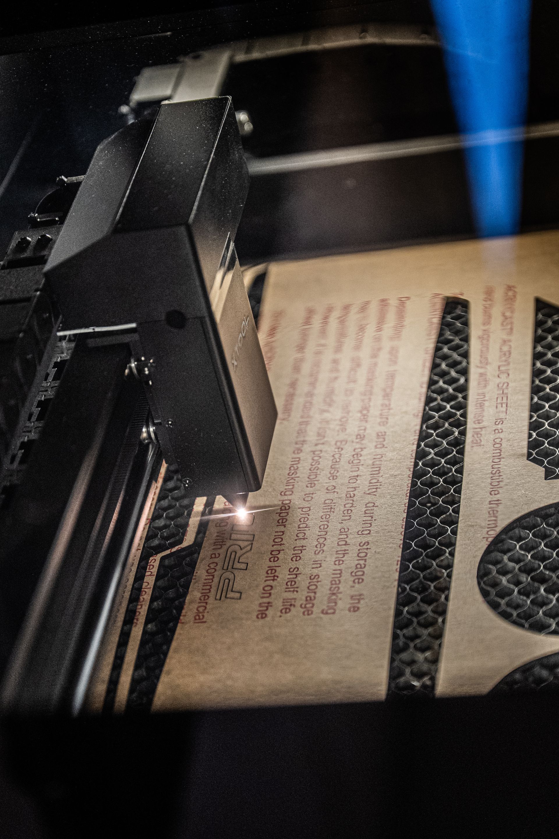 Laser cutter etching text onto cardboard stencil.