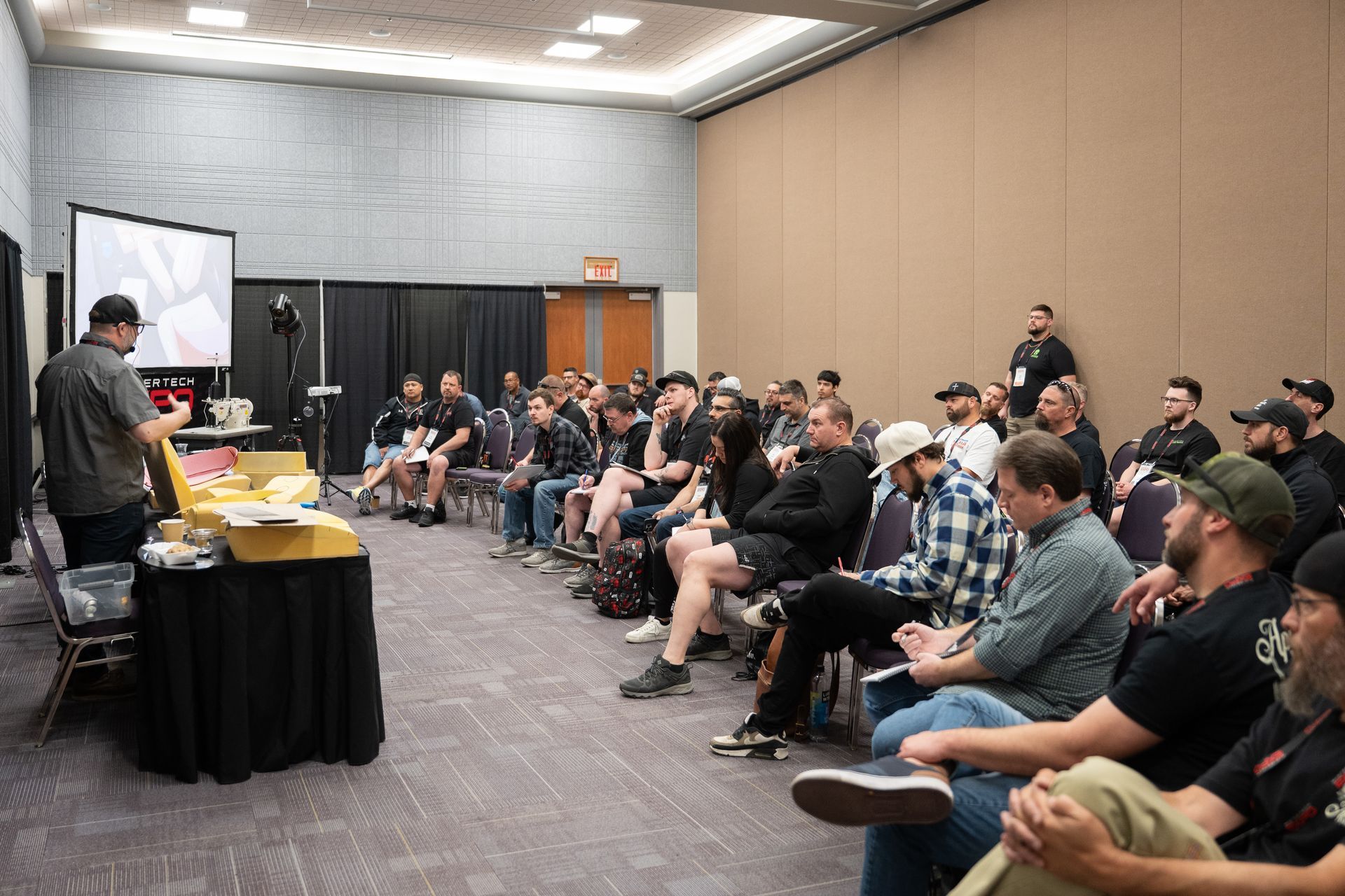 A speaker giving a presentation to a seated audience in a conference room.
