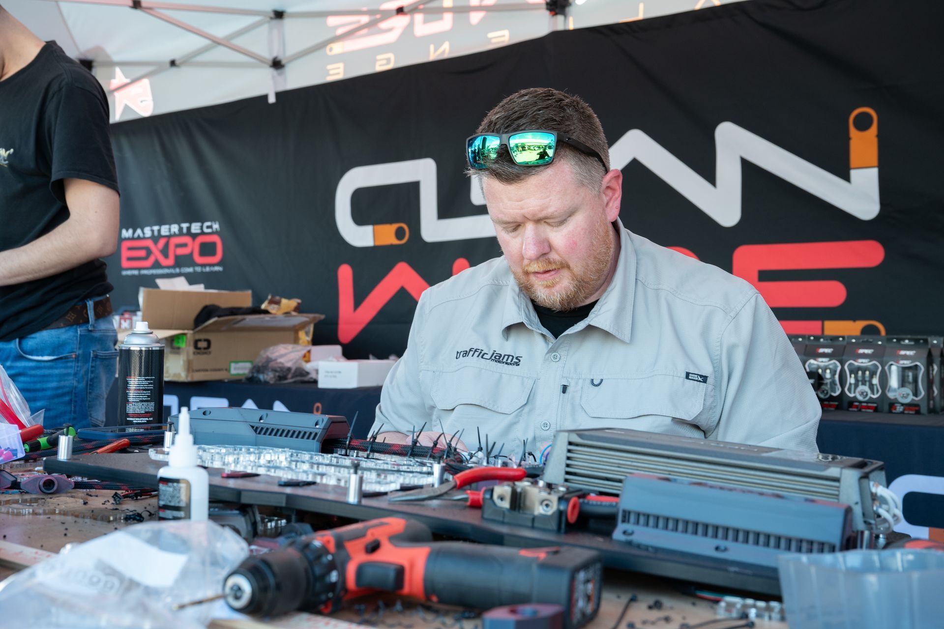 Man working on electrical components at a trade show booth with 