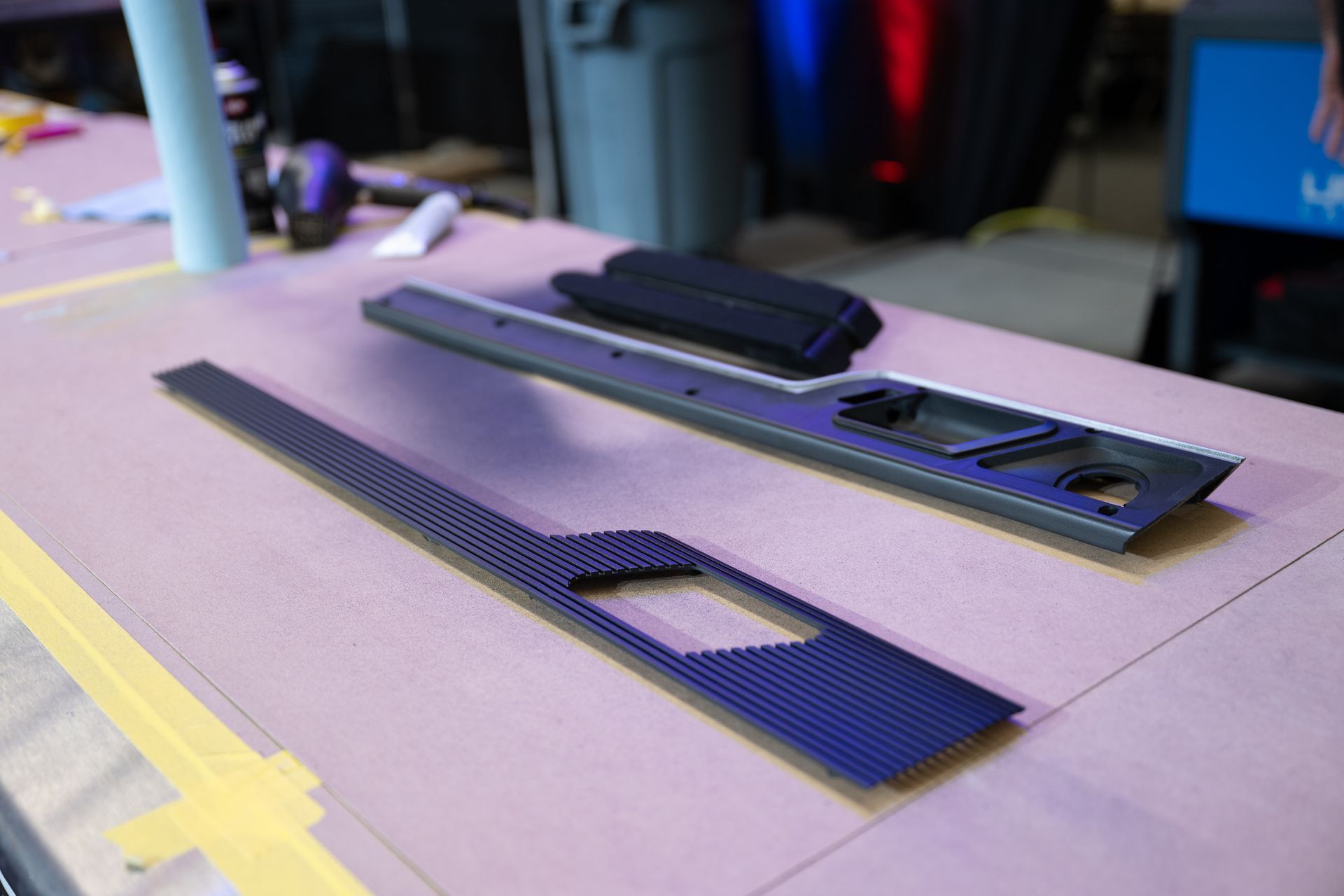 Two black carbon fiber panels and a dark gray frame on a workbench.