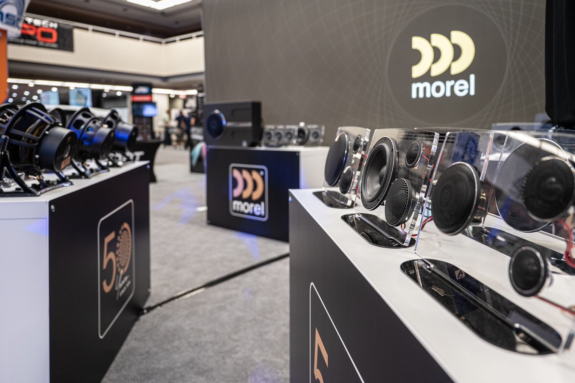 Morel audio equipment display at a trade show, featuring speakers and the company logo.