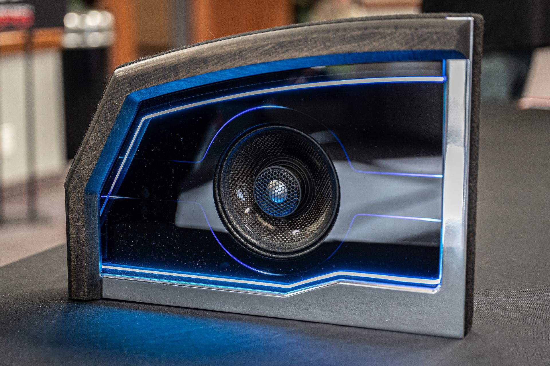 A rectangular display case with a blue glowing outline, showing a blurred image of a car and a lens.