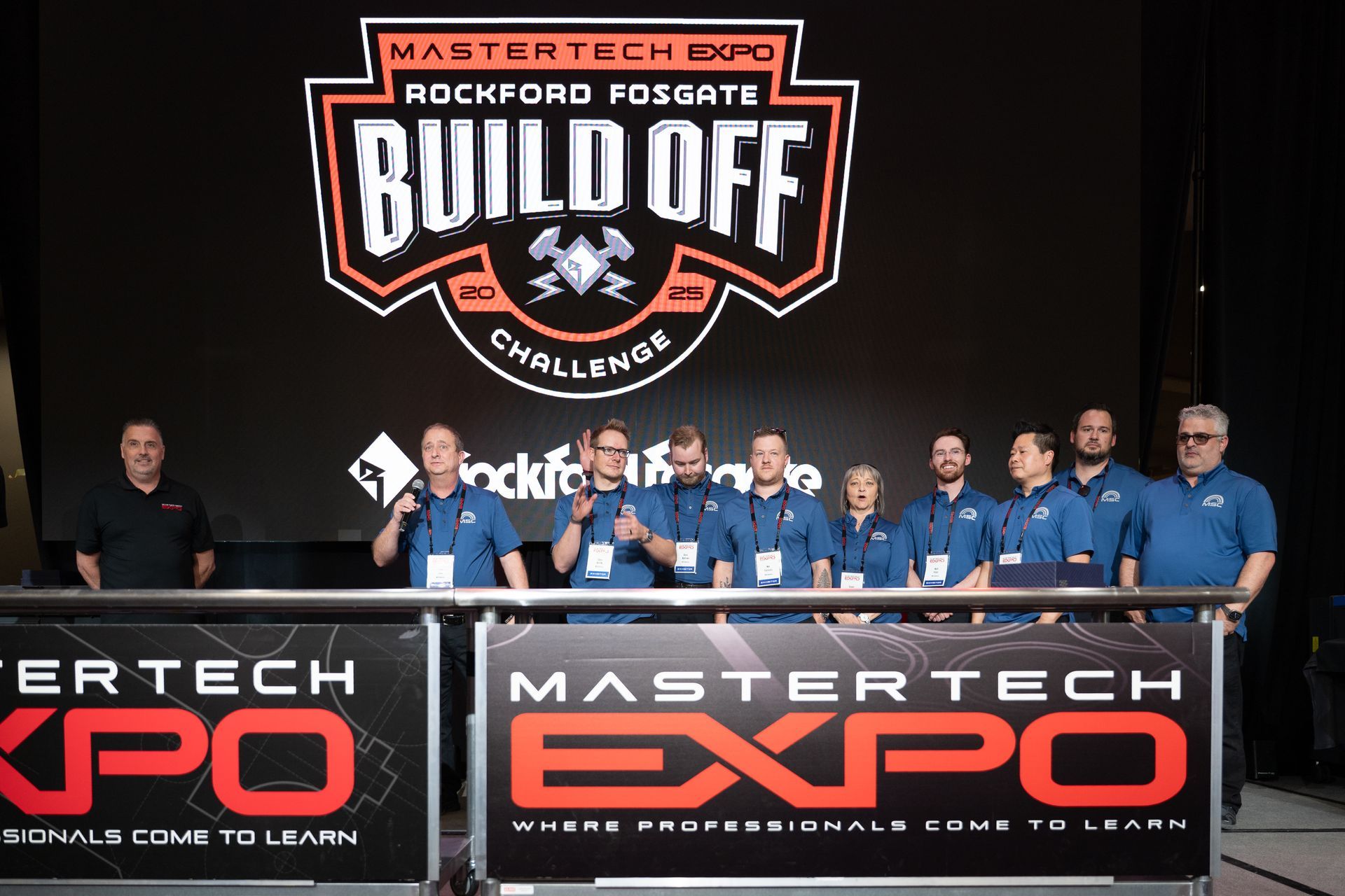 Mastertech Expo Build Off challenge. Group of people in blue shirts, banner with logo.