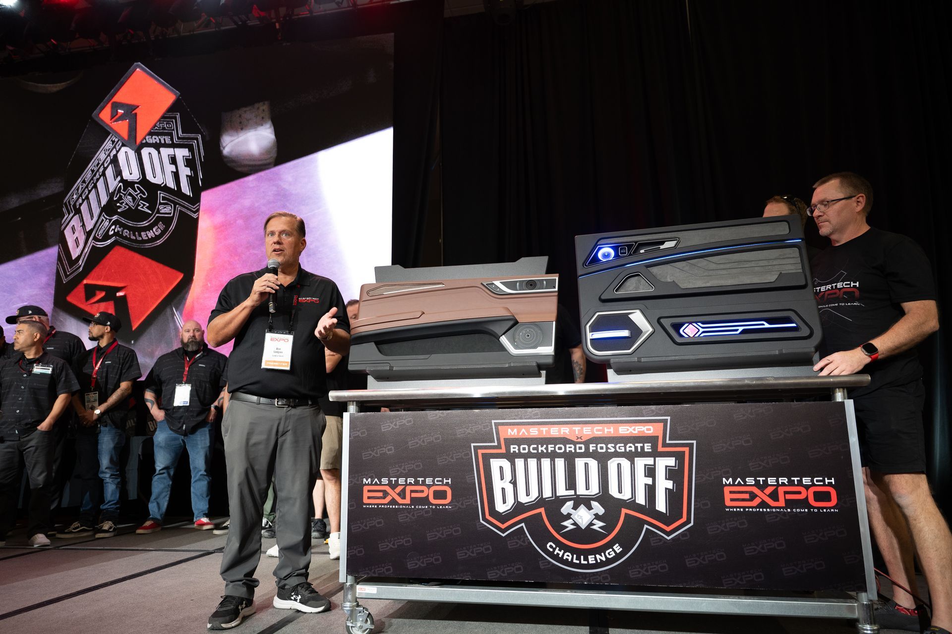 Man speaking at Auto Expo Build Off, showcasing custom car panels.