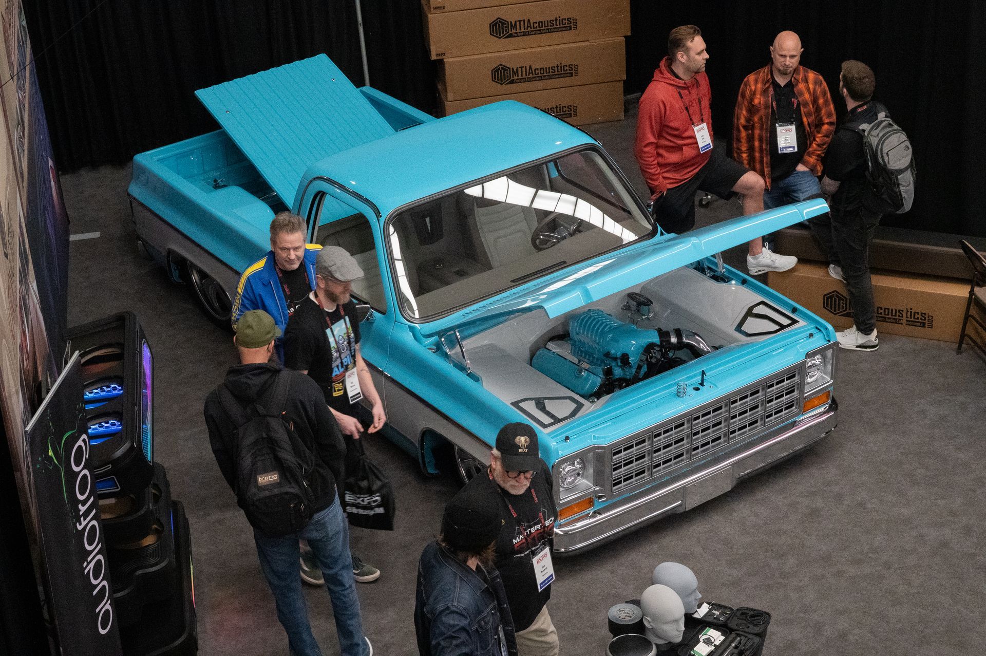 Light blue custom pickup truck at a car show, hood open, attracting a crowd.