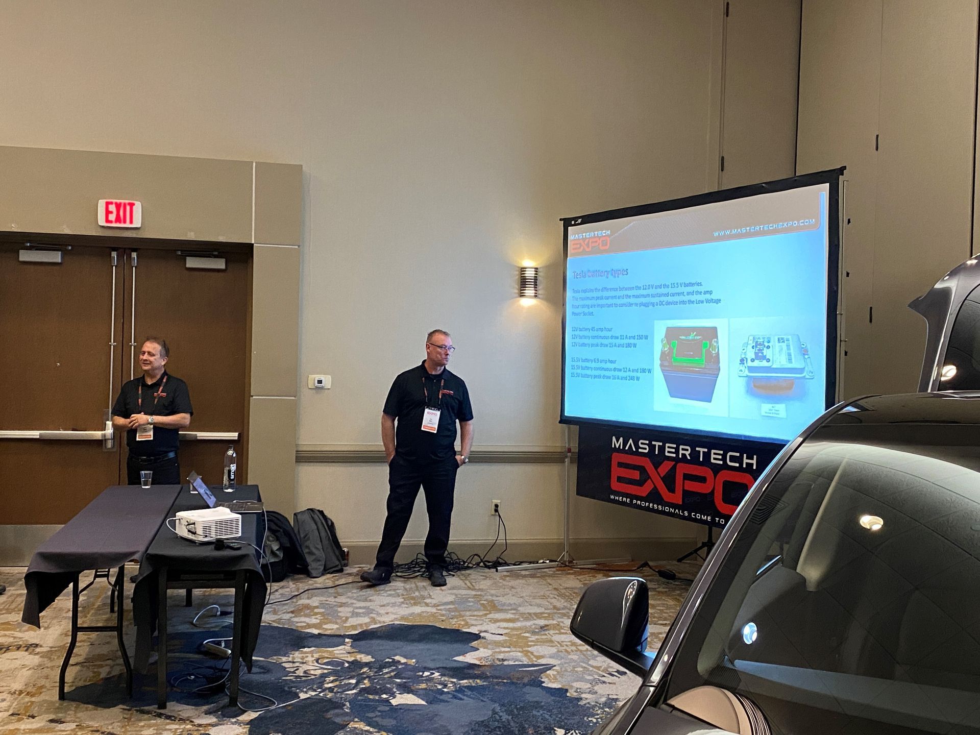 A man is giving a presentation in front of a large screen in a room.
