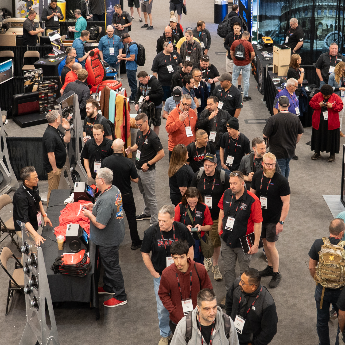 Crowd at trade show, many people walking, standing, some looking at displays.
