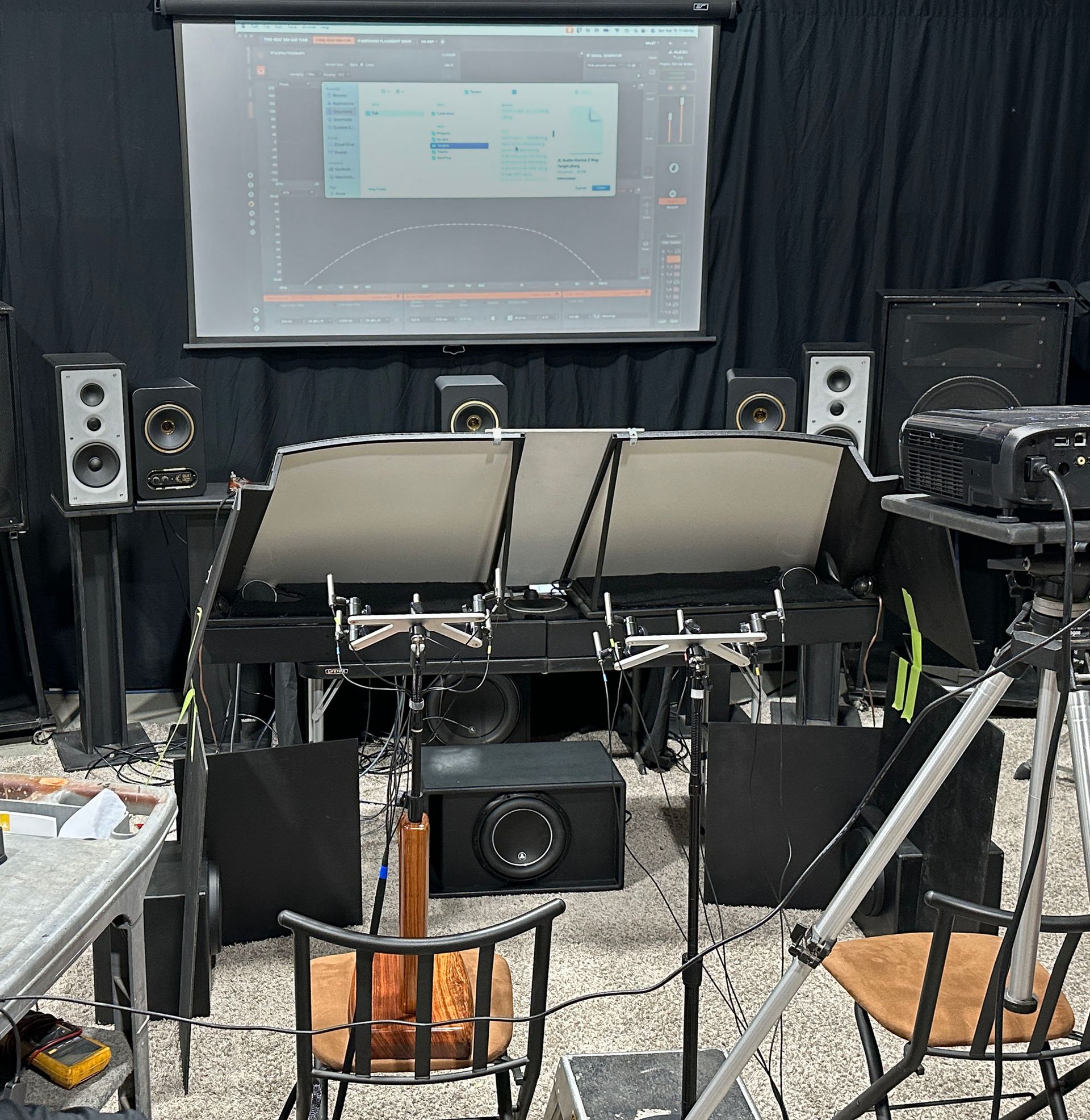 Recording studio setup with speakers, screens, and equipment; a projector displays a graph.
