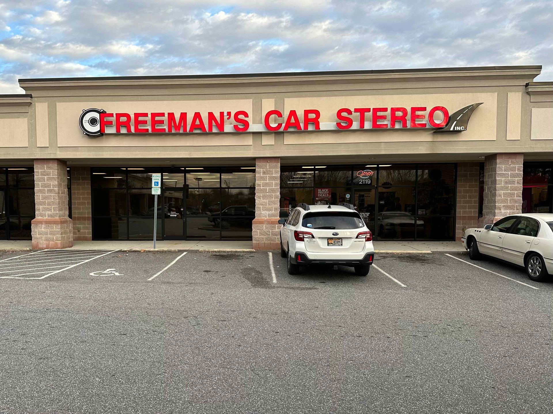 A car stereo store with cars parked in front of it.