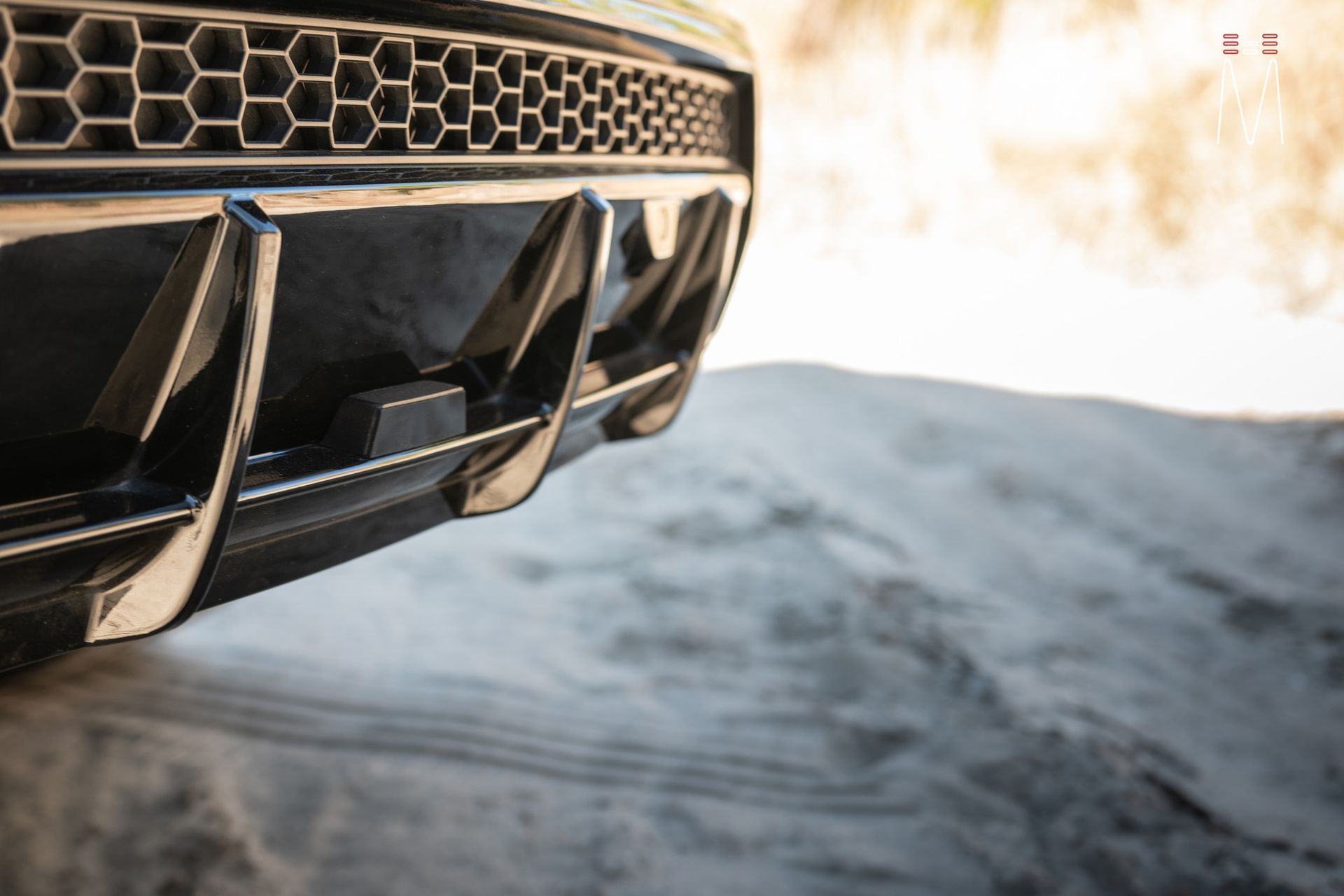 A close up of a car 's bumper on a dirt road.