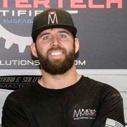 A man with a beard is wearing a hat and a black shirt.