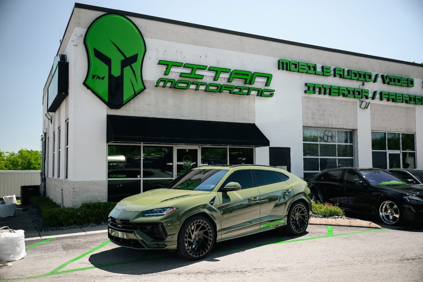 A green car is parked in front of a building with a spartan helmet on it.