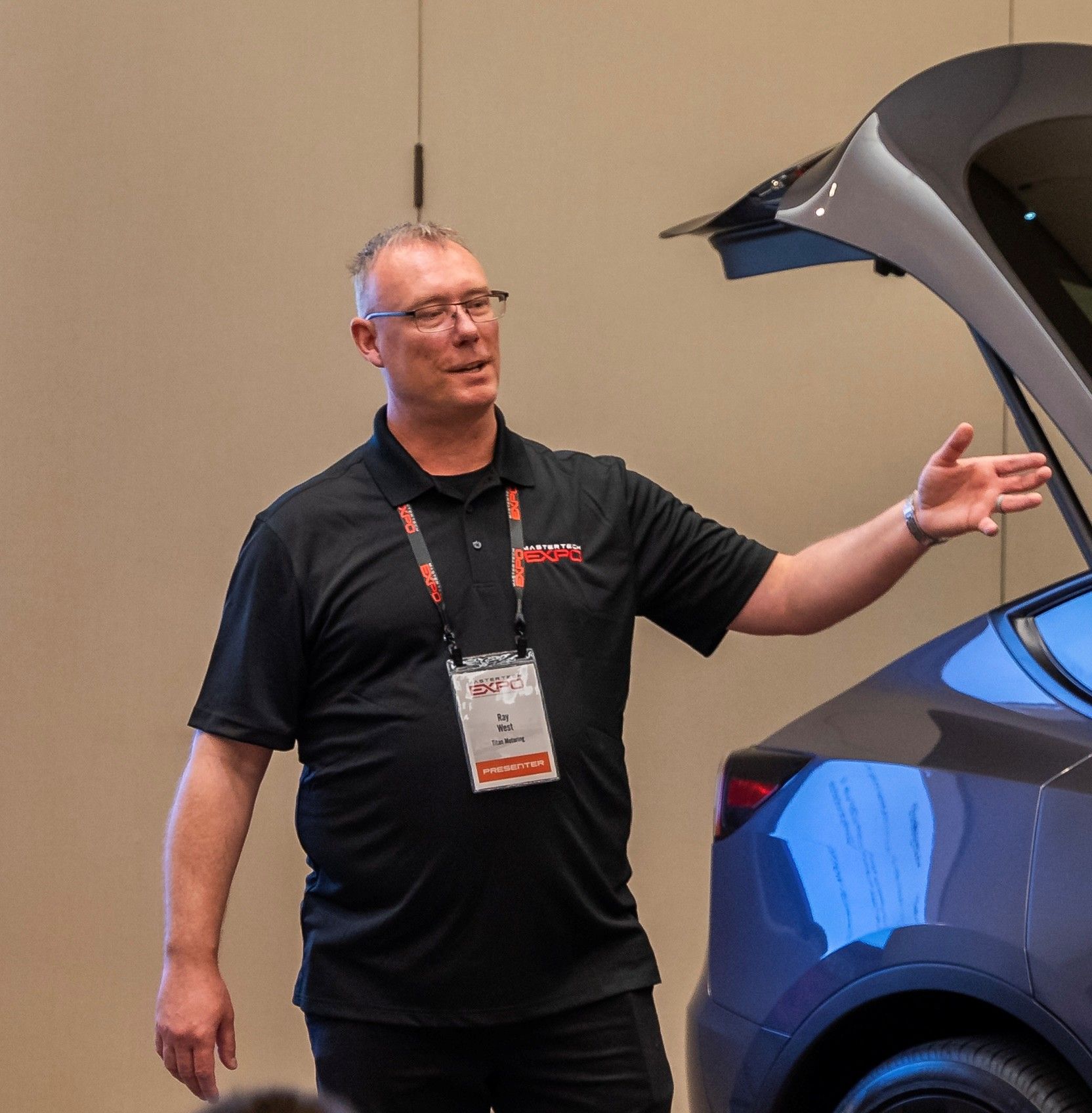 A man standing in front of a car with the trunk open