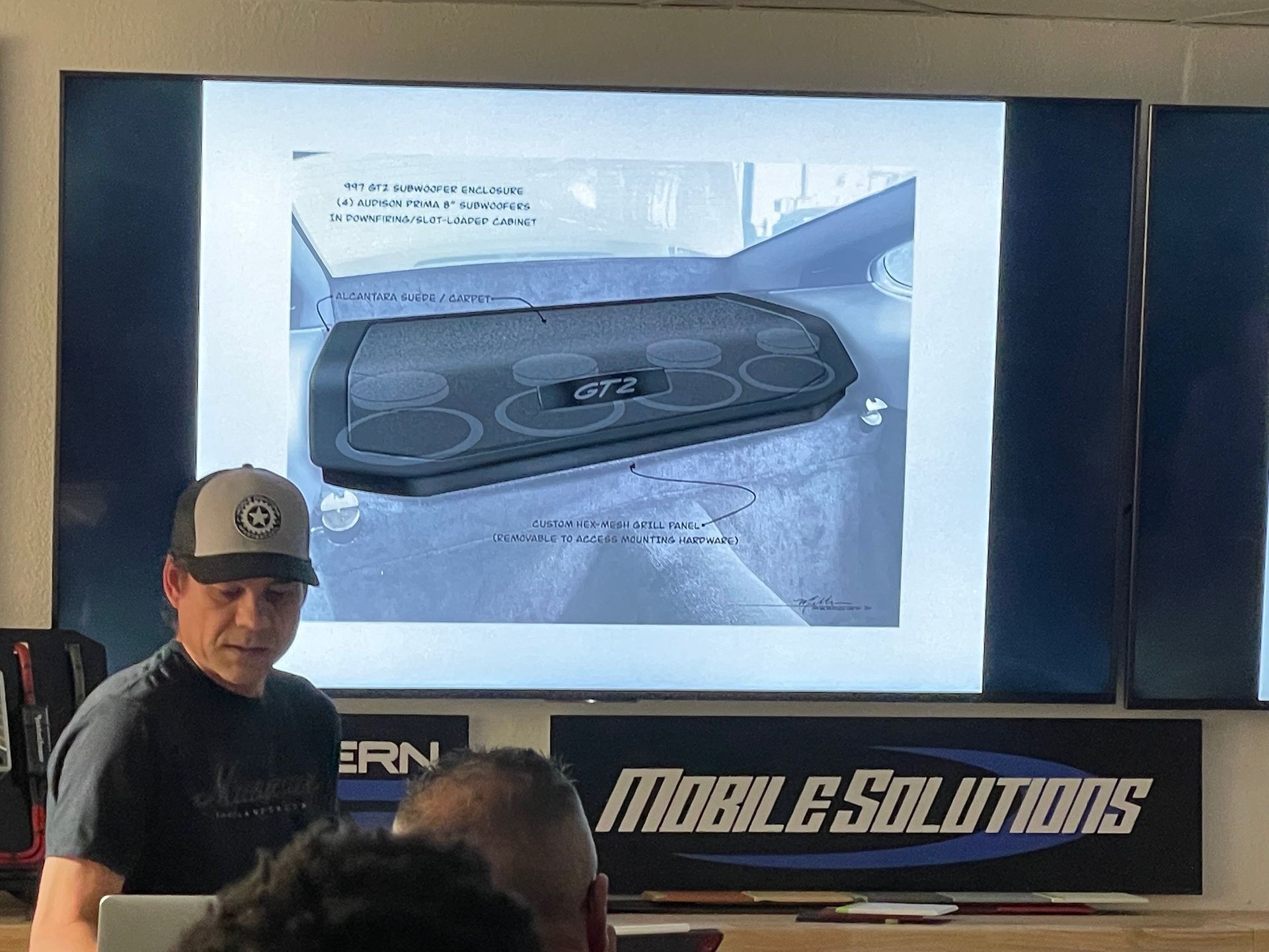 A man is giving a presentation in front of a screen that says mobile solutions