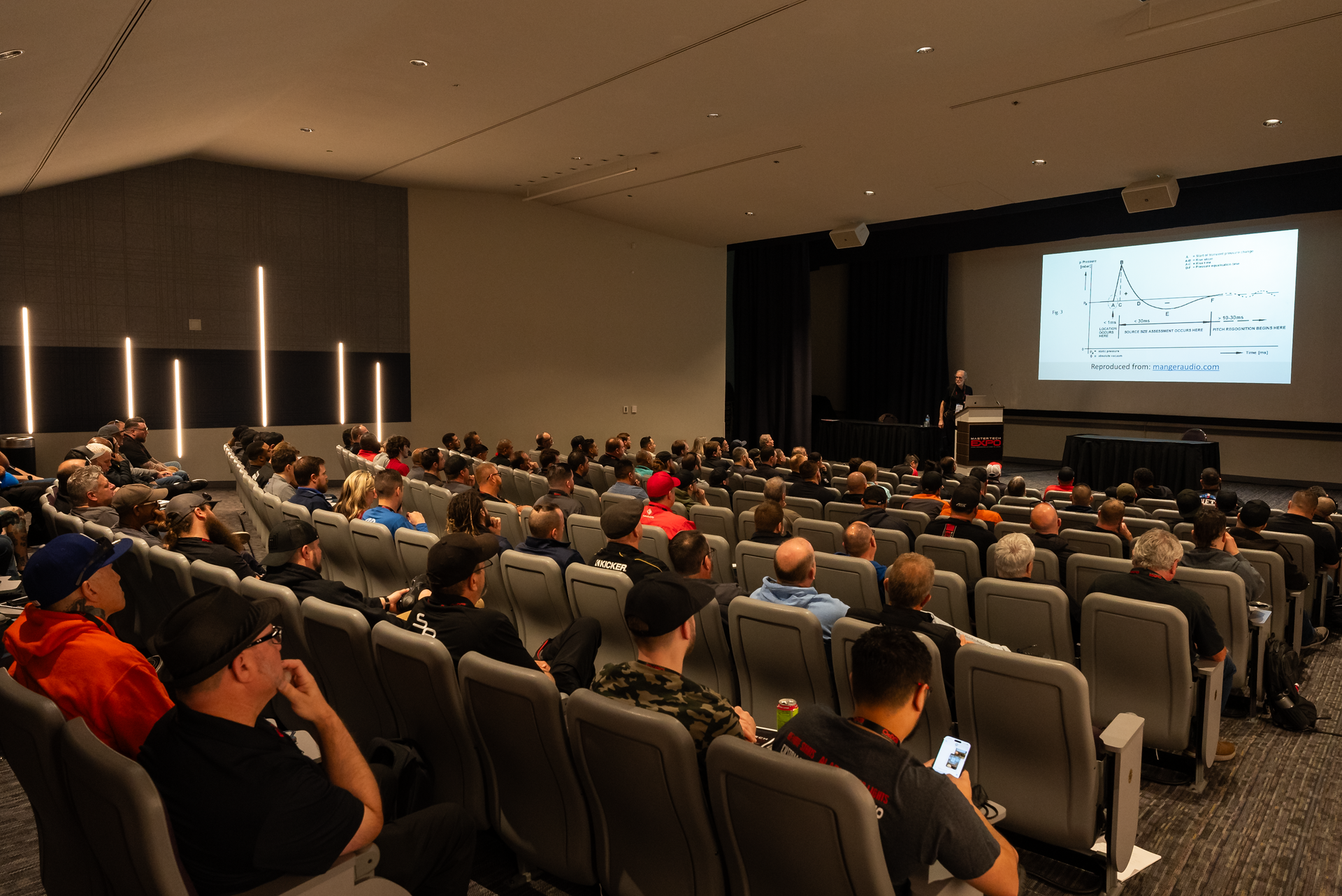 A large group of people are sitting in an auditorium watching a presentation.