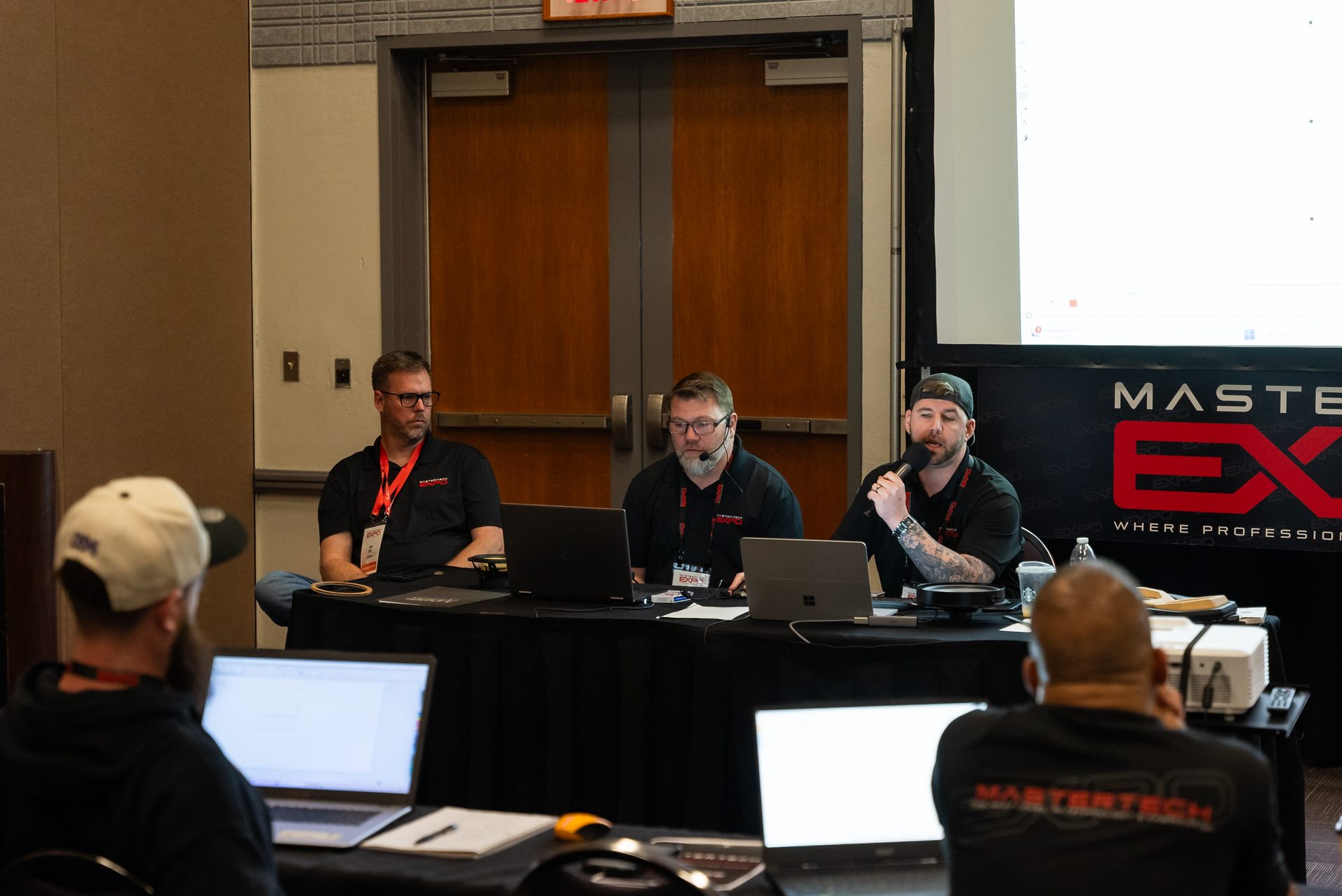 A group of men are sitting at a table with laptops.
