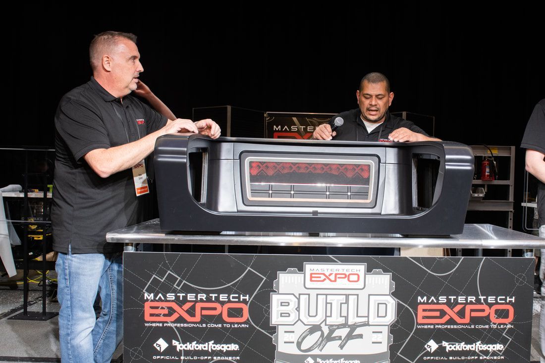 Two men are standing in front of a sign that says build off