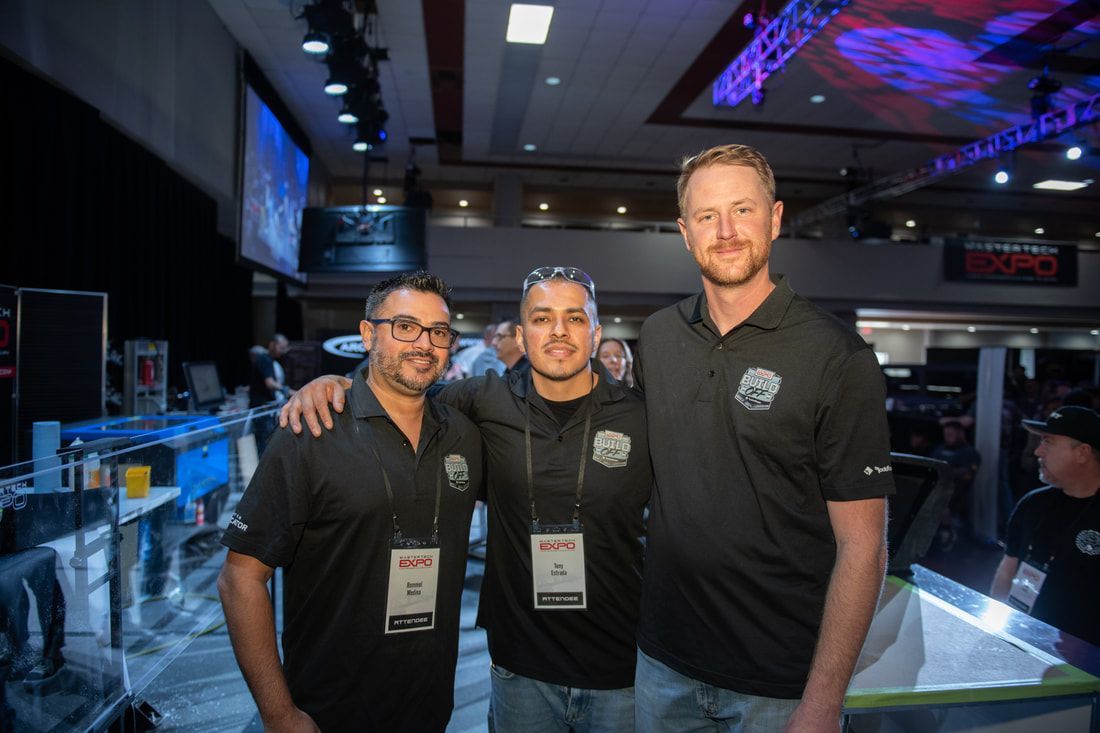 Three men are posing for a picture together at a convention.