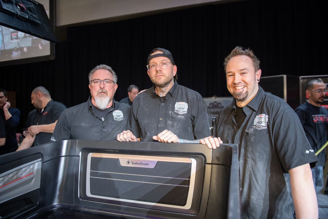 Three men are standing next to each other holding a large object.