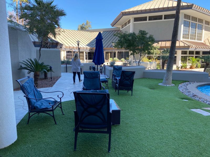 Outdoor patio with blue furniture, artificial turf, and a person walking.