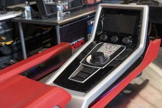 Red and silver control panel with a screen and various buttons, likely for a vehicle or machine.