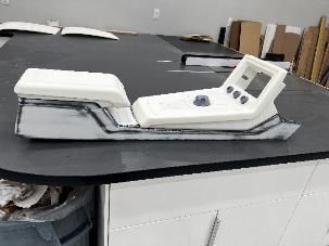 White and gray console prototype with buttons and screen on a table.