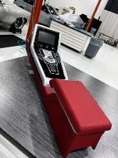 Red and white car console with screen and armrest in a workshop.