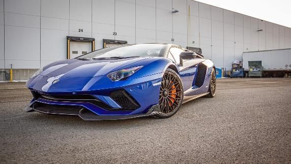 A blue lamborghini aventador is parked in front of a building.