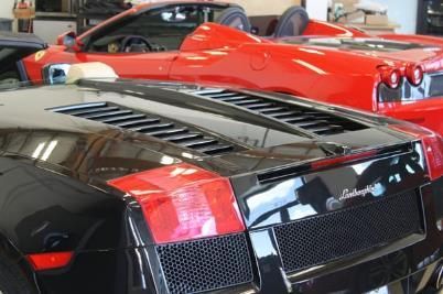 A black lamborghini is parked next to a red sports car