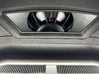A subwoofer is sitting in the trunk of a car.