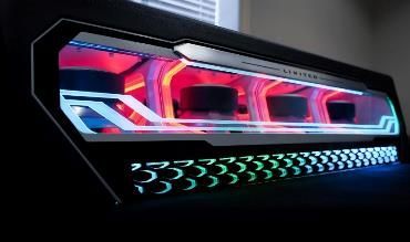 A computer case with a lot of lights on it is sitting in front of a window.