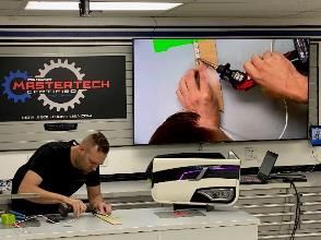 A man is working on a car door in a garage.