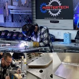 A man is welding a piece of metal in a workshop.