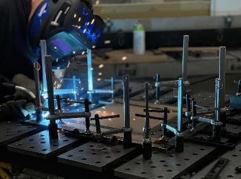 A man is welding a piece of metal in a factory.