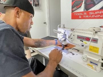 A man is sitting at a table using a sewing machine.