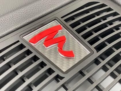 A close up of a grille with a red letter m on it.