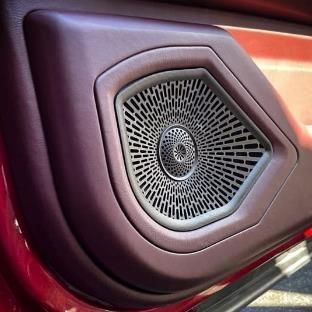 A close up of a car door speaker in a red car.