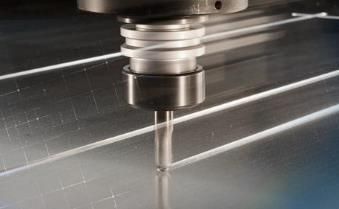 A machine is cutting a piece of metal on a table.