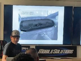 Man presenting a dashboard design on a screen. Mobile Solutions logo present.