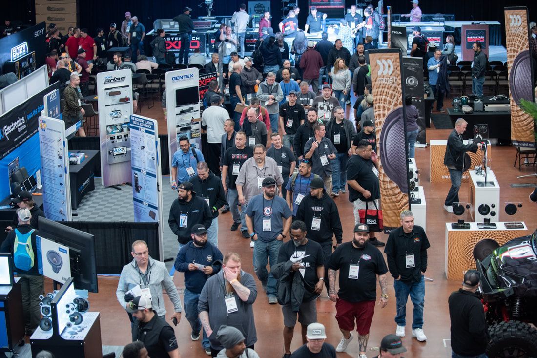 A large group of people are walking through a convention center.